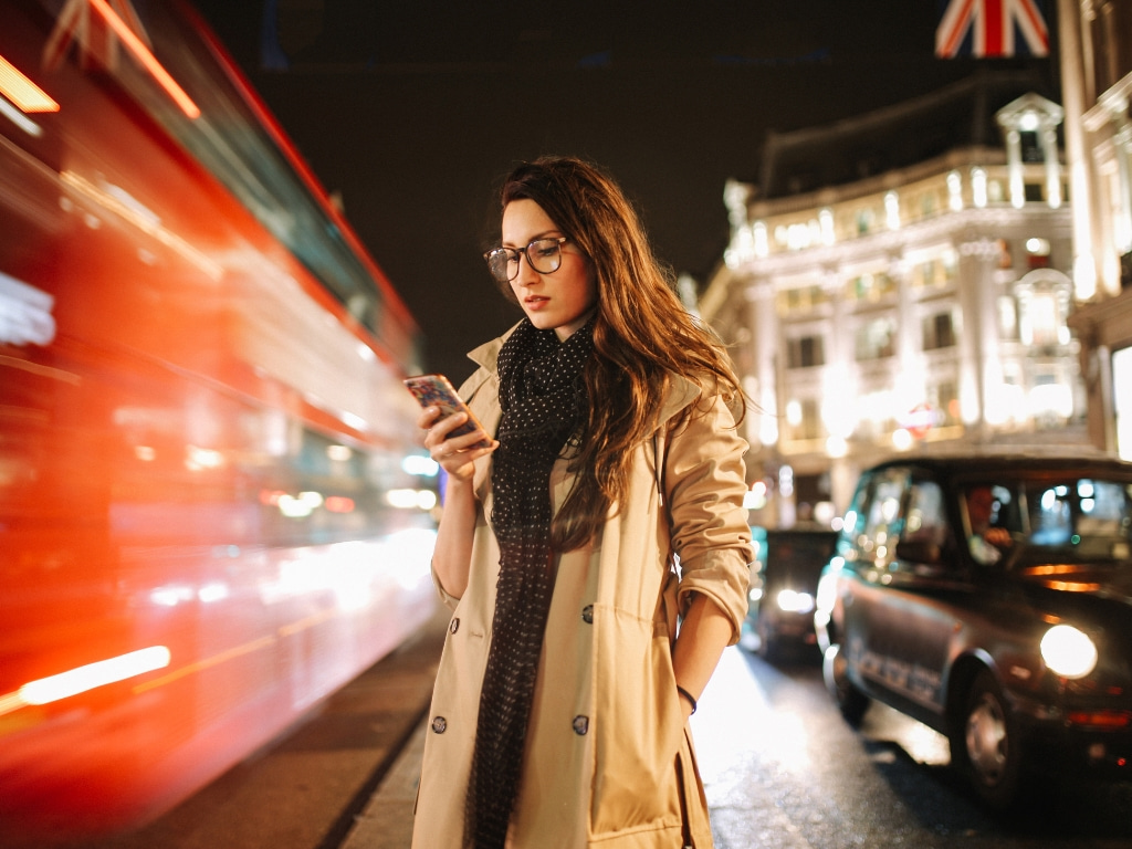 woman-using-phone-street-red-bus